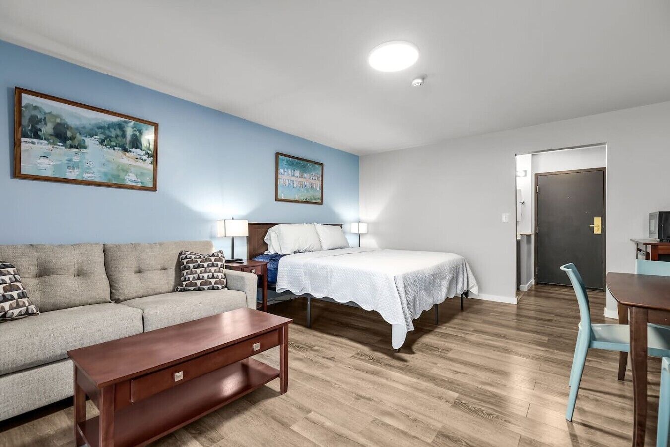 A room with a bed, a sofa, a wooden coffee table, and a desk with a chair.