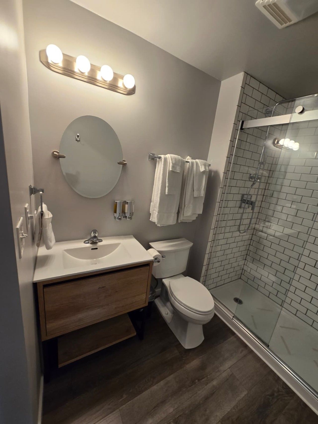 A modern bathroom with a vanity, sink, mirror, and a glass-enclosed shower.