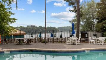 A swimming pool with a fenced deck area, outdoor seating, and a view of a body of water.