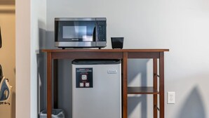A compact kitchenette with a microwave and a refrigerator, a wooden table, and a QR code for room information. - Victorian Inn #115 | 2 Queen Beds (Elkhart Lake)