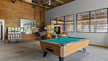 A pool table in a room with wooden walls and large windows.