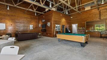 Un grand espace intérieur comprenant une table de billard, des sièges et une table de jeu de billard.
