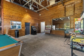 A wooden interior with a pool table, a trash bin, a vending machine, and a claw machine. - Victorian Inn #116 | 2 Queen Beds (Elkhart Lake)