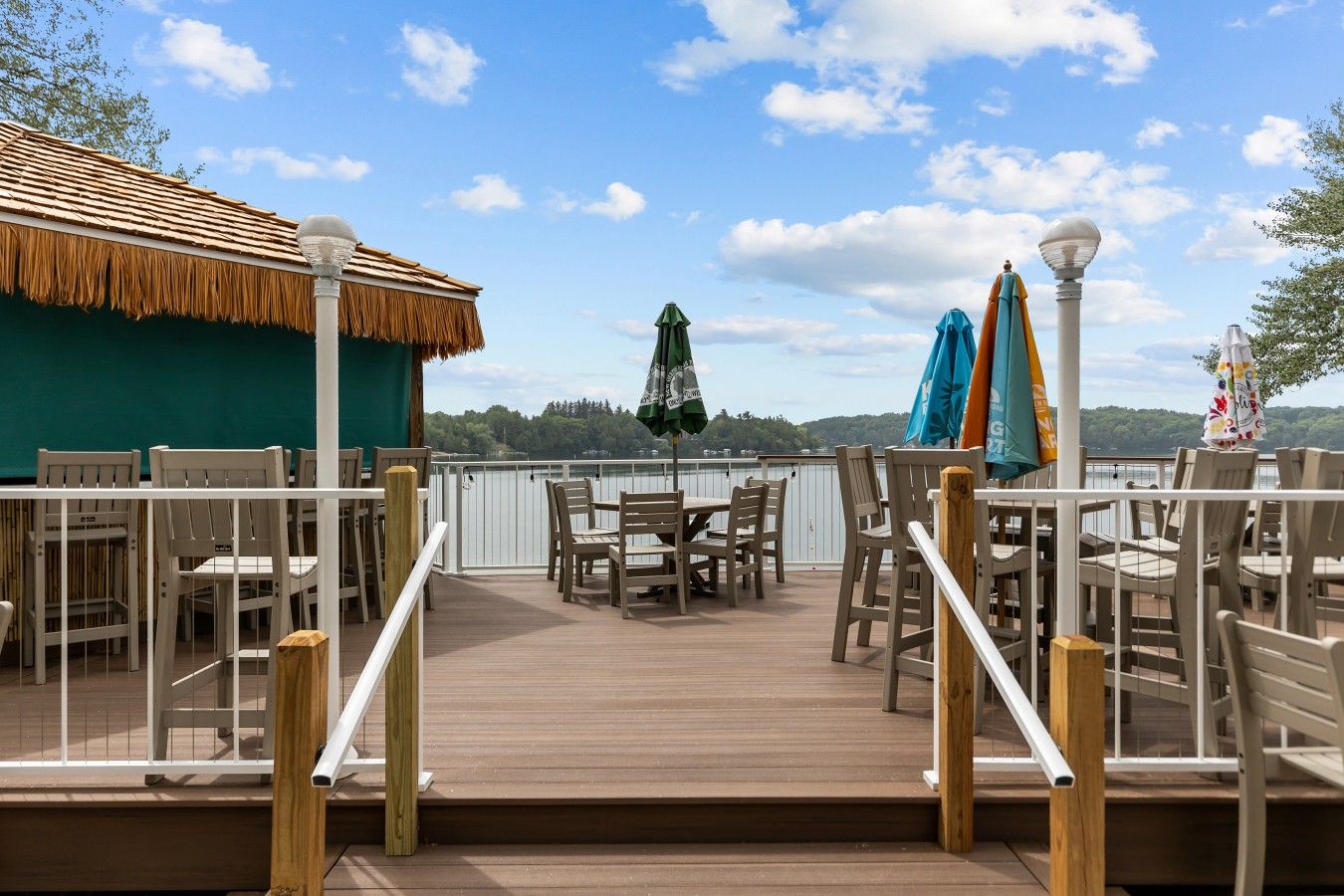 Een terras met zitplaatsen buiten, een constructie met rieten dak en uitzicht op het water.