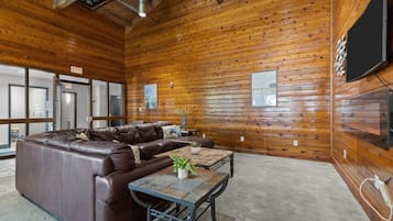 A room with a leather sectional sofa, a small table with a plant, and wooden walls.
