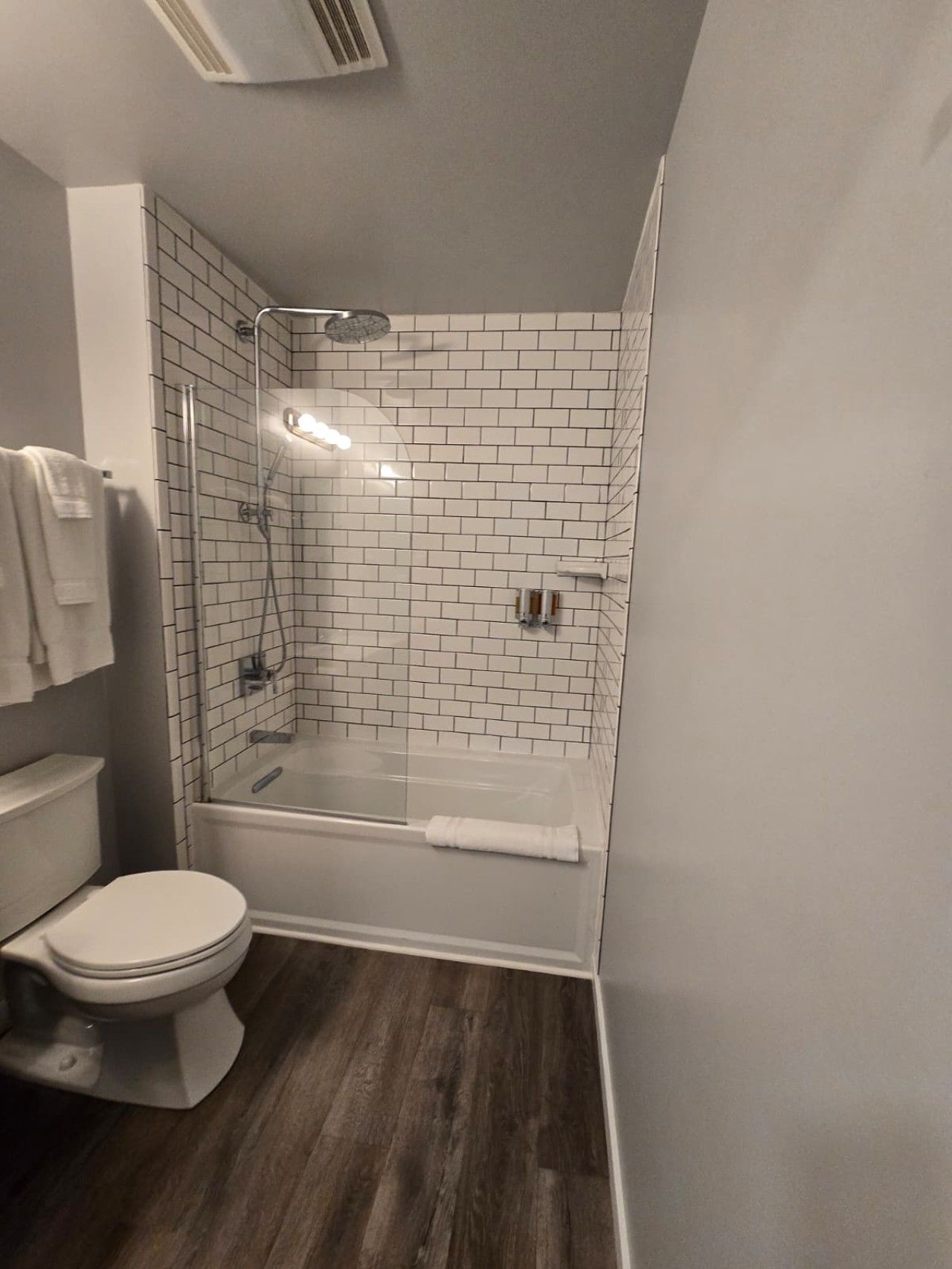 Um banheiro com vaso sanitário, box de chuveiro com porta de vidro e banheira.