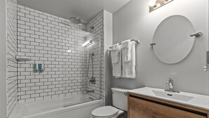 Un baño con una bañera blanca, inodoro, lavabo y espejo.