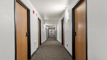 Ein Hotelkorridor mit Teppichböden, Holztüren und Wandleuchten.