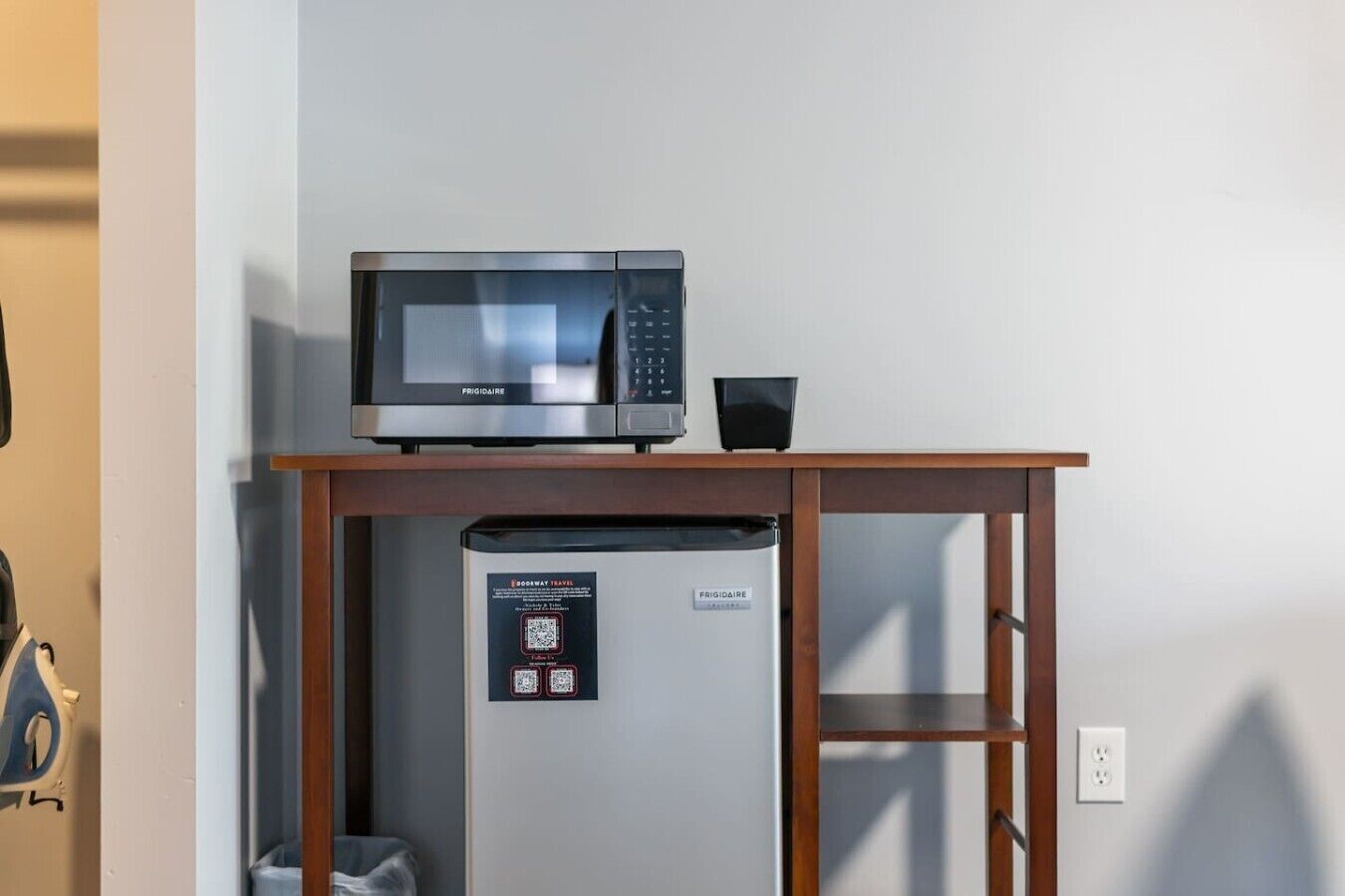 Une petite cuisine équipée d’un four à micro-ondes et d’un réfrigérateur, d’une table en bois et d’un code QR donnant accès aux informations sur la chambre.