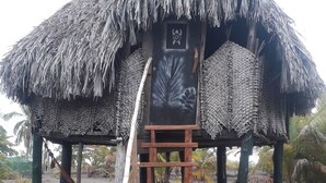 Ein Gebäude mit einem Strohdach und einer Holztreppe, die zu einer Tür mit einem dekorativen Wappen führt.
