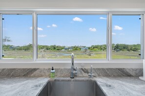 Eine Küche mit Spüle, einem Fenster und Blick auf eine grüne Landschaft.