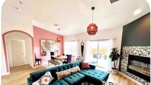 Een woonkamer met een groene bank, een ronde salontafel en een open haard.