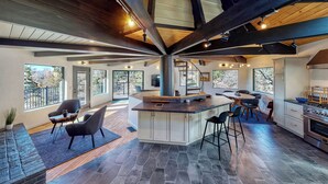 A spacious kitchen with a central island, large windows, and a high ceiling with exposed beams. - 3-BEDROOM, 3-BATH ARCHITECTURAL MARVEL IN LAKE ARROWHEAD (Lake Arrowhead)