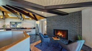 A modern kitchen with a large island, a fireplace, and a dining area with chairs. - 3-BEDROOM, 3-BATH ARCHITECTURAL MARVEL IN LAKE ARROWHEAD (Lake Arrowhead)
