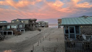 A beachside property with multiple wooden structures, including a main building and several smaller cabins, connected by a wooden deck. - Beach Dreamer with Ocean Views, 120 Steps to the Beach • Buxton, NC, OBX (Buxton)