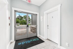 A hotel entrance with a glass door, a black mat with 'CHRISTINE' on it, and a white door labeled '1'.
