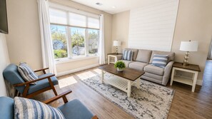 Una sala de estar con un sofá, sillones, una mesa de centro y vistas al exterior.