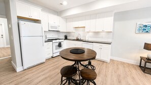 Una cocina moderna con armarios blancos, una isla central y un comedor con una mesa redonda.
