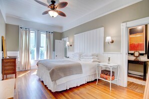 Ein Schlafzimmer mit Bett, Nachttisch, Schminktisch und Deckenventilator.