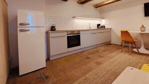 Eine kompakte Küche mit weißen Schränken, einem eingebauten Backofen und einer kleinen Essecke mit Tisch und Stühlen.