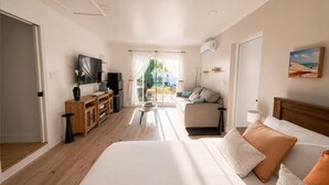 Ett hotellrum med en säng, en tv, ett skrivbord och utsikt över omgivningarna.