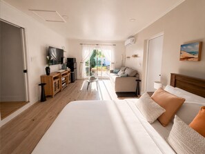 Ein Hotelzimmer mit Bett, Fernseher, Schreibtisch und Blick ins Freie.