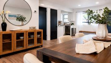 Un comedor moderno con una mesa de madera, sillas, un espejo y un jarrón con flores.