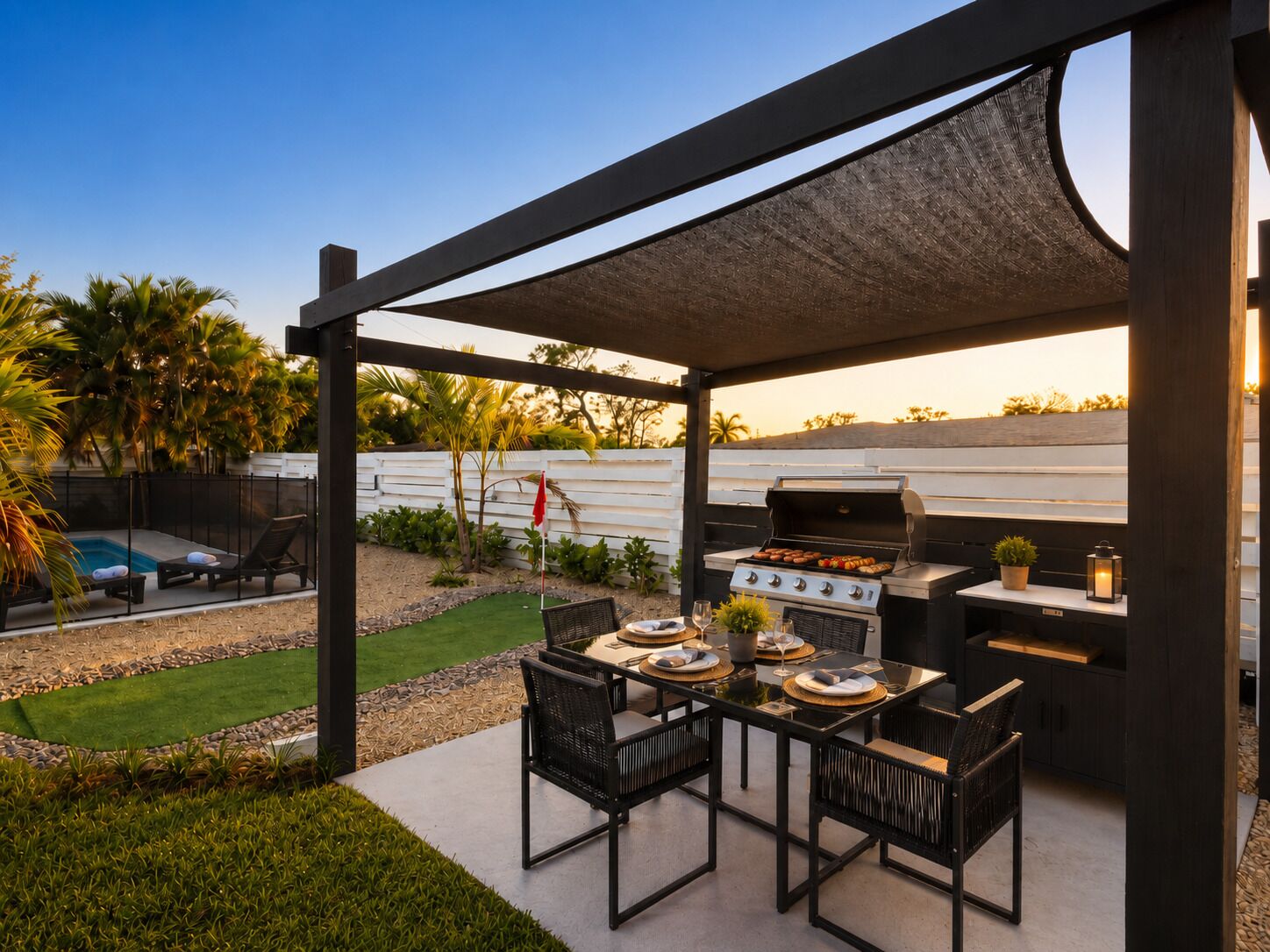 Un patio exterior con una parrilla, asientos y una piscina.