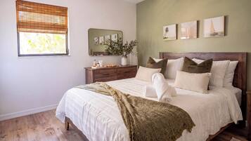 Un dormitorio con cama, cabecera de madera, mesitas de noche, un espejo y cuadros en la pared.