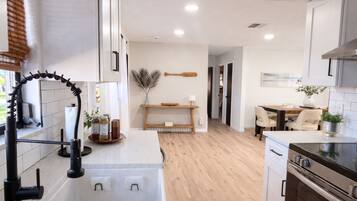 Una cocina moderna con encimera de madera, horno empotrado y comedor con mesa y sillas.