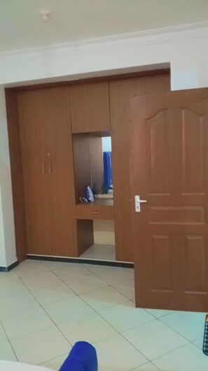 Ein Zimmer mit großem Kleiderschrank, einer Tür und einem gefliesten Boden.