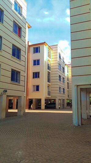 Ein mehrstöckiges Gebäude mit Innenhof, Balkonen und Fußgängerzone.