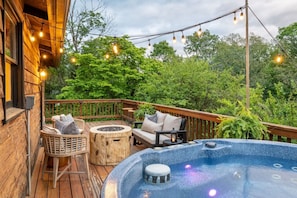 Een houten terras met buitenmeubilair, een jacuzzi en lichtslingers.