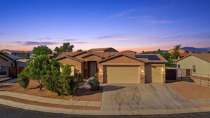 A residential area with houses featuring solar panels, a driveway, and a clear sky. - Luxury Private Pool & Spa Home | Resort Backyard | Sleeps 10 (Tucson)