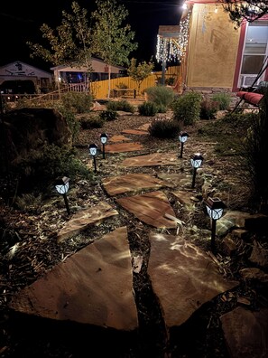 Ein stimmungsvoller Gartenpfad bei Nacht mit Steinplatten und dekorativen Laternen.