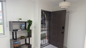Un pasillo con una estantería, una puerta con reja de metal y una lámpara en el techo.