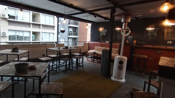 A café with tables and chairs, a counter, and hanging lights. - Mediterranea Hostel (Córdoba)