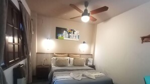 A hotel room with a bed, a ceiling fan, a poster on the wall, and a window with curtains. - Mediterranea Hostel (Córdoba)