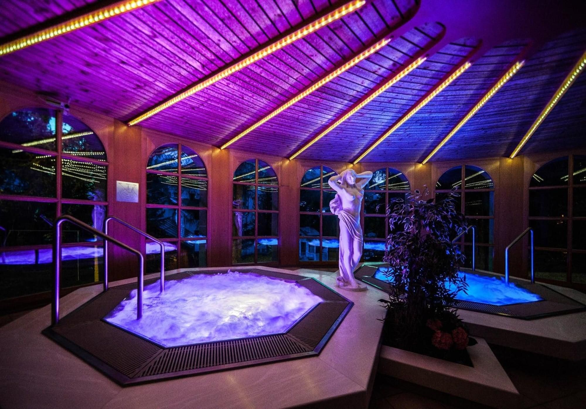 Wellnessbereich mit Whirlpool, einer Statue und Deckenleuchten.