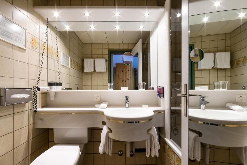 Un baño con dos lavamanos, un inodoro y un espejo.