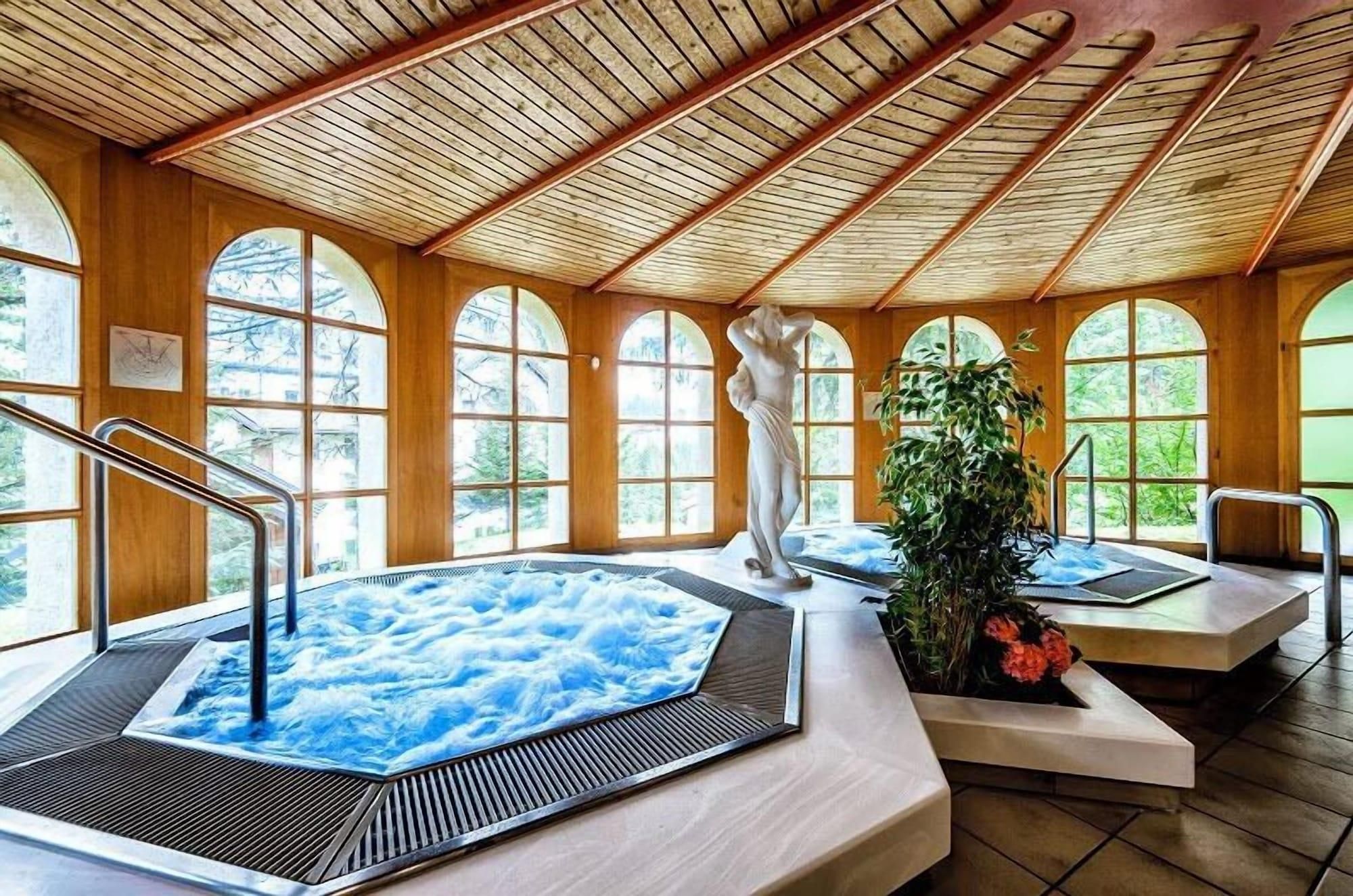Ein Spa-Bereich mit Holzarchitektur, großen Bogenfenstern und zwei Whirlpools.