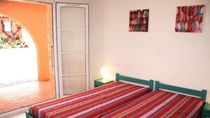 Ein Zimmer mit einem Bett, einem Nachttisch, einer Lampe und zwei Wandbildern.