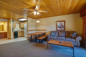 A cozy living area with a wooden ceiling, a sofa, a dining table, and a kitchen in the background. - Suite at the Eagle Wing of the Lodge at Angel Fire Resort (Angel Fire)