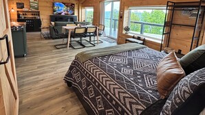Interior acolhedor de uma cabana com cama, espaço de refeições, TV e cantinho do café.
