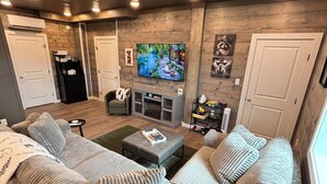 Uma sala de estar com um amplo sofá modular, uma lareira, uma televisão e teto de madeira.