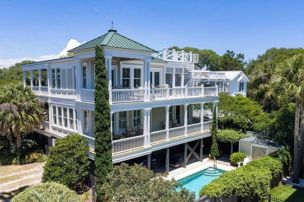 A two-story house with a balcony, a pool, and lush greenery. - Private Pool + Rooftop Ocean Views (Isle Of Palms)