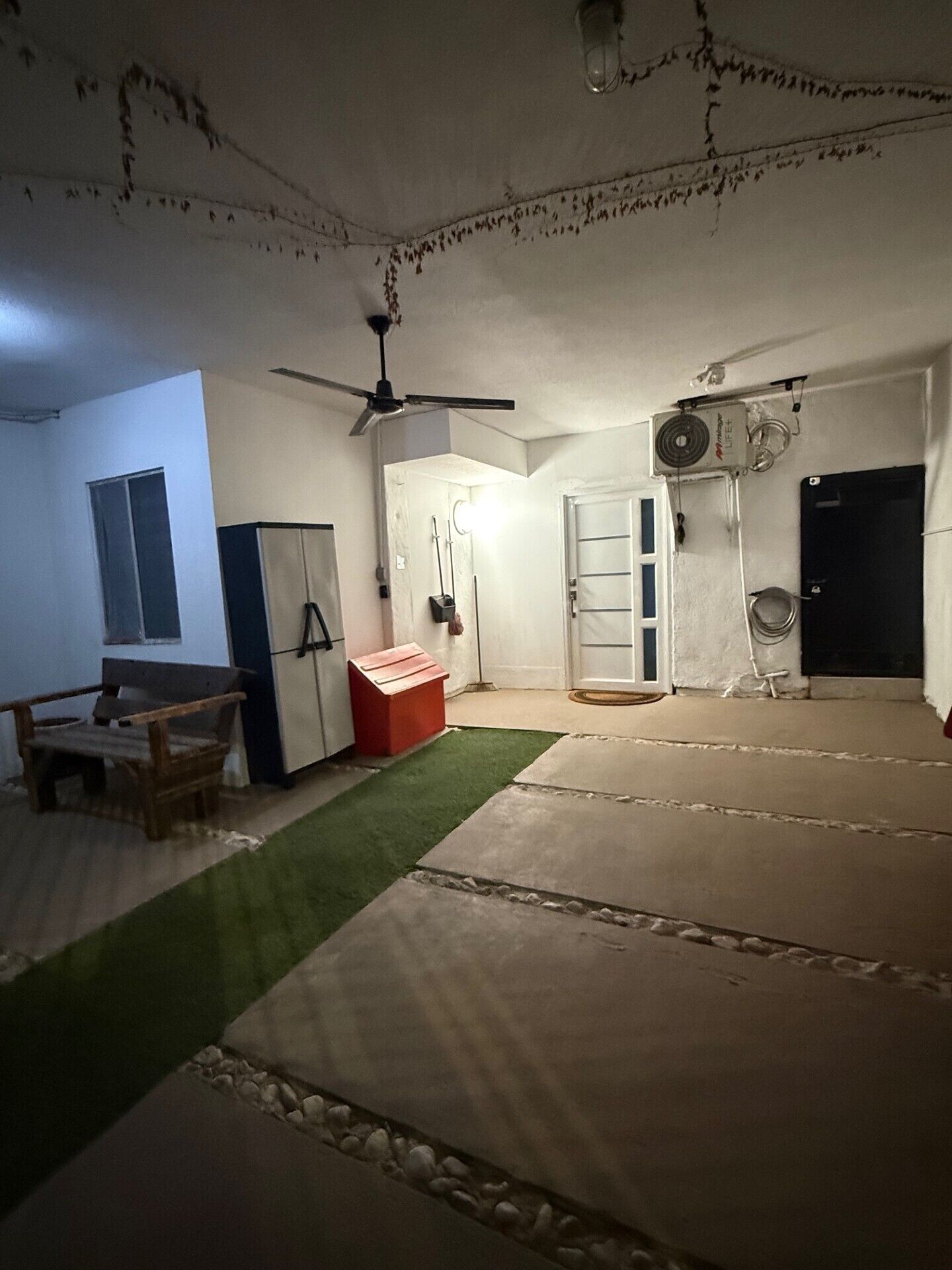 Ein Zimmer mit Deckenventilator, Heizung, Tür, Bank und kleinem Tisch.