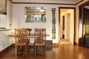 A dining area with a wooden table and chairs, a large mirror above the table, and a decorative wall hanging. -  Peaceful 3-bedroom house with AC in Beautiful Hanchett Park Area (San Jose)