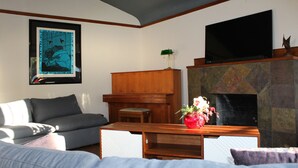 Ein Wohnzimmer mit einer Couch, einem Flachbildfernseher, einem Kamin und einem gerahmten Bild an der Wand.