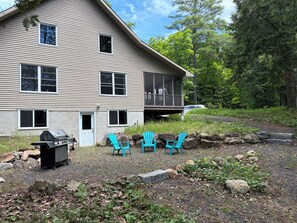 A two-story house with a porch, a grill, and three blue chairs. - Forest retreat with private waterfalls (Mississippi Mills)
